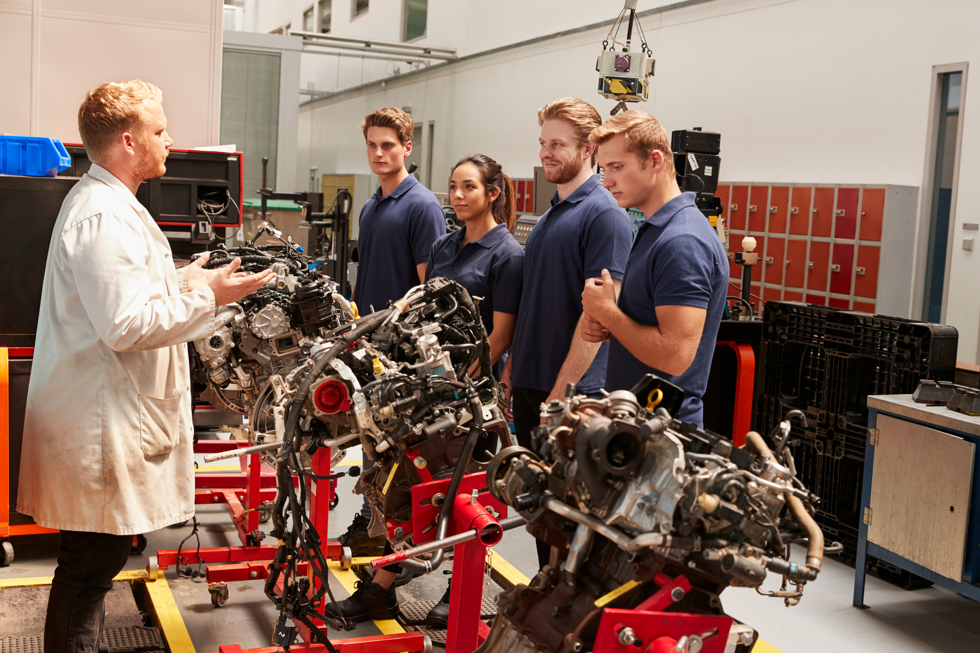 Apprentices Studying Car Engines with a Mechanic